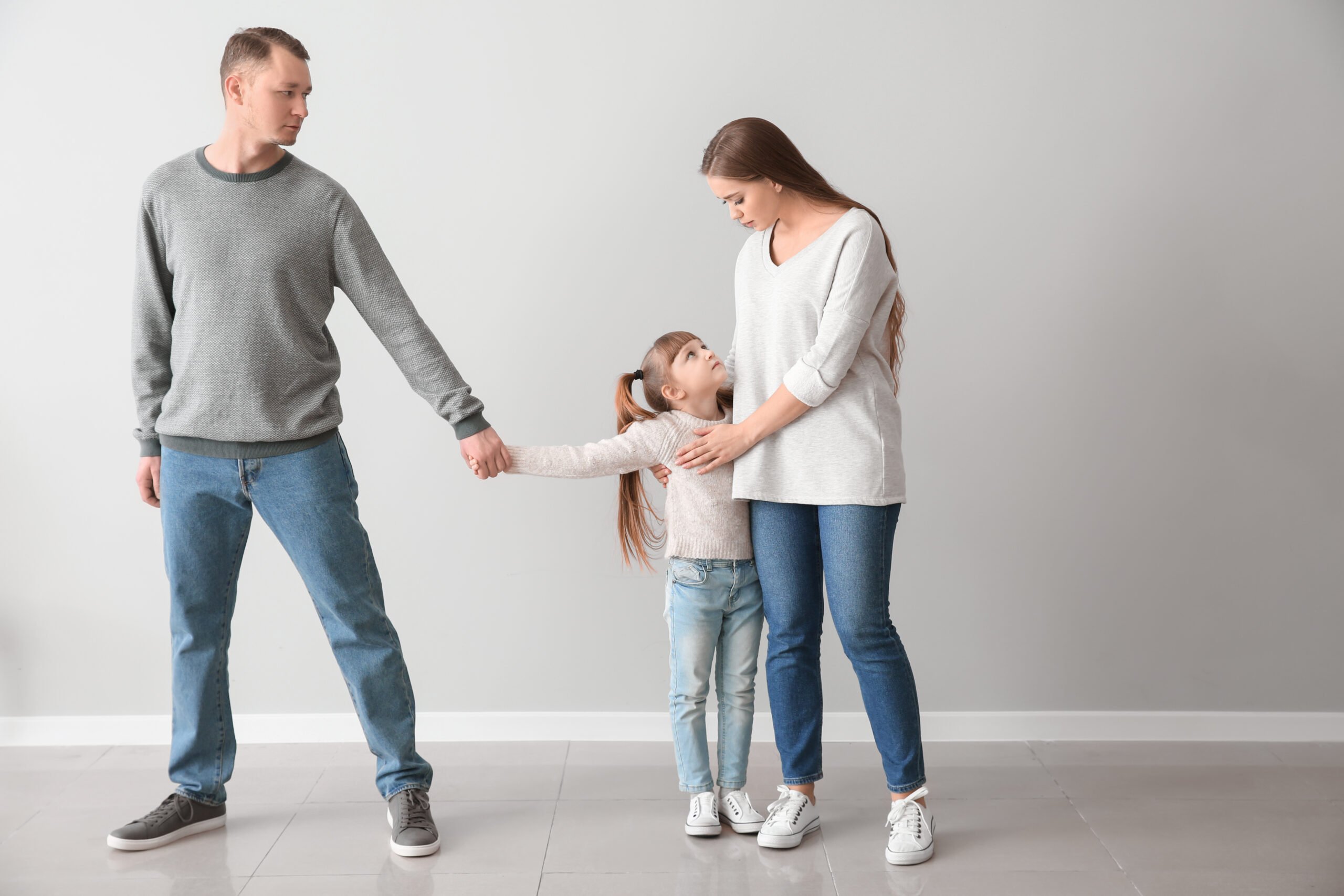 Unhappy family after divorce against light wall