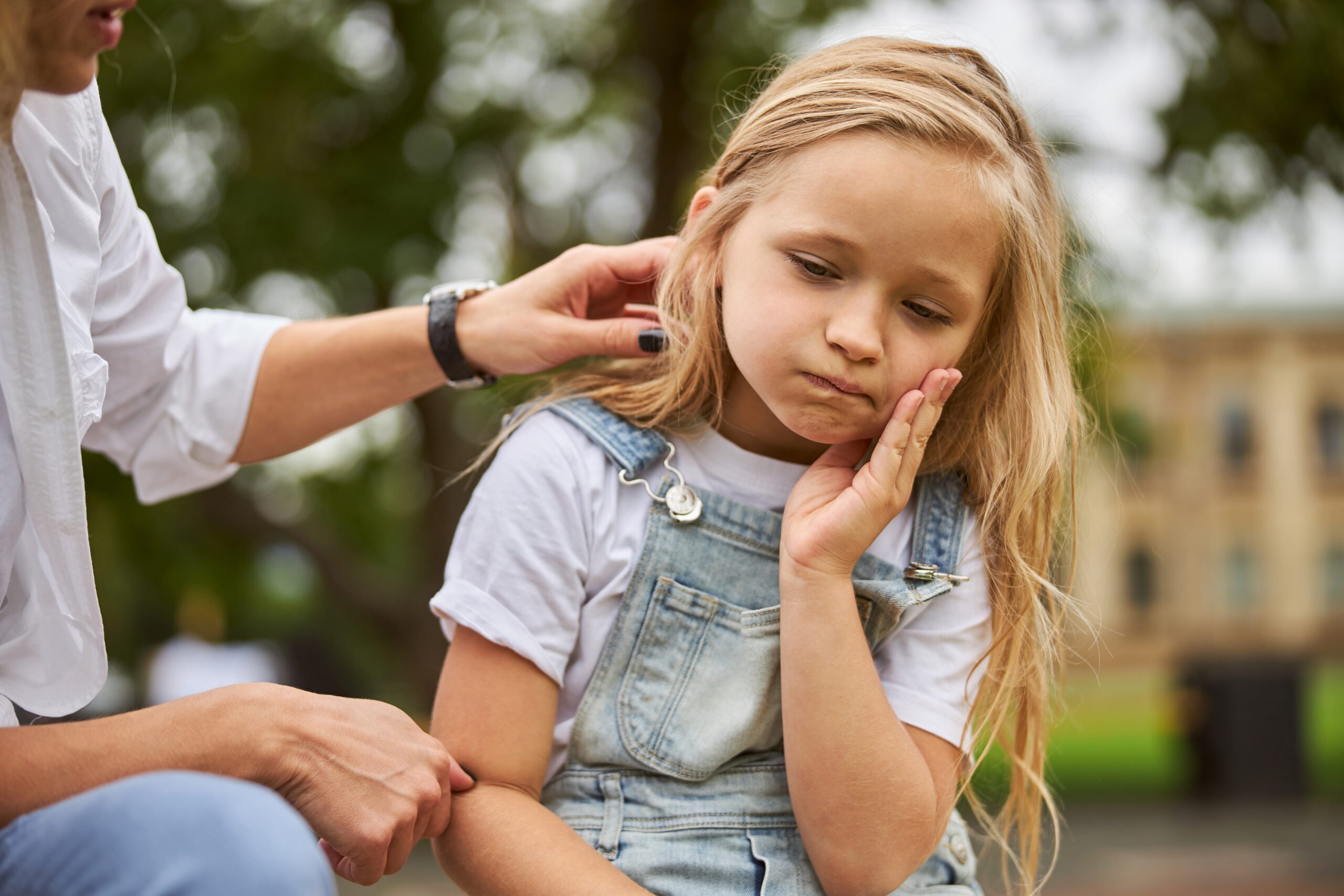 Portrait of pretty lovable little girl propping up her face at summer green park
