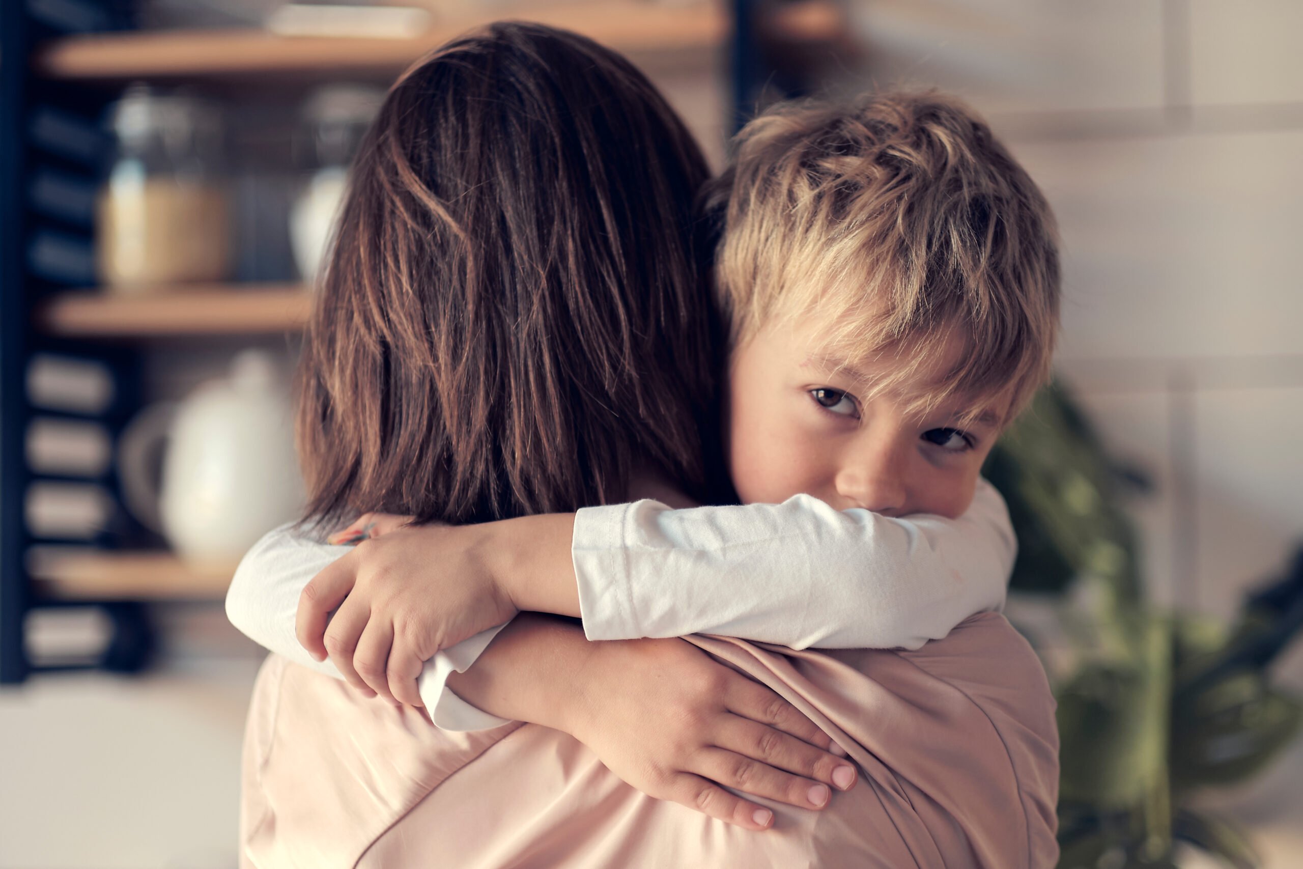 mother carries the child in her arms, little boy lies in his mother's shoulder and smiles. son hugs mom