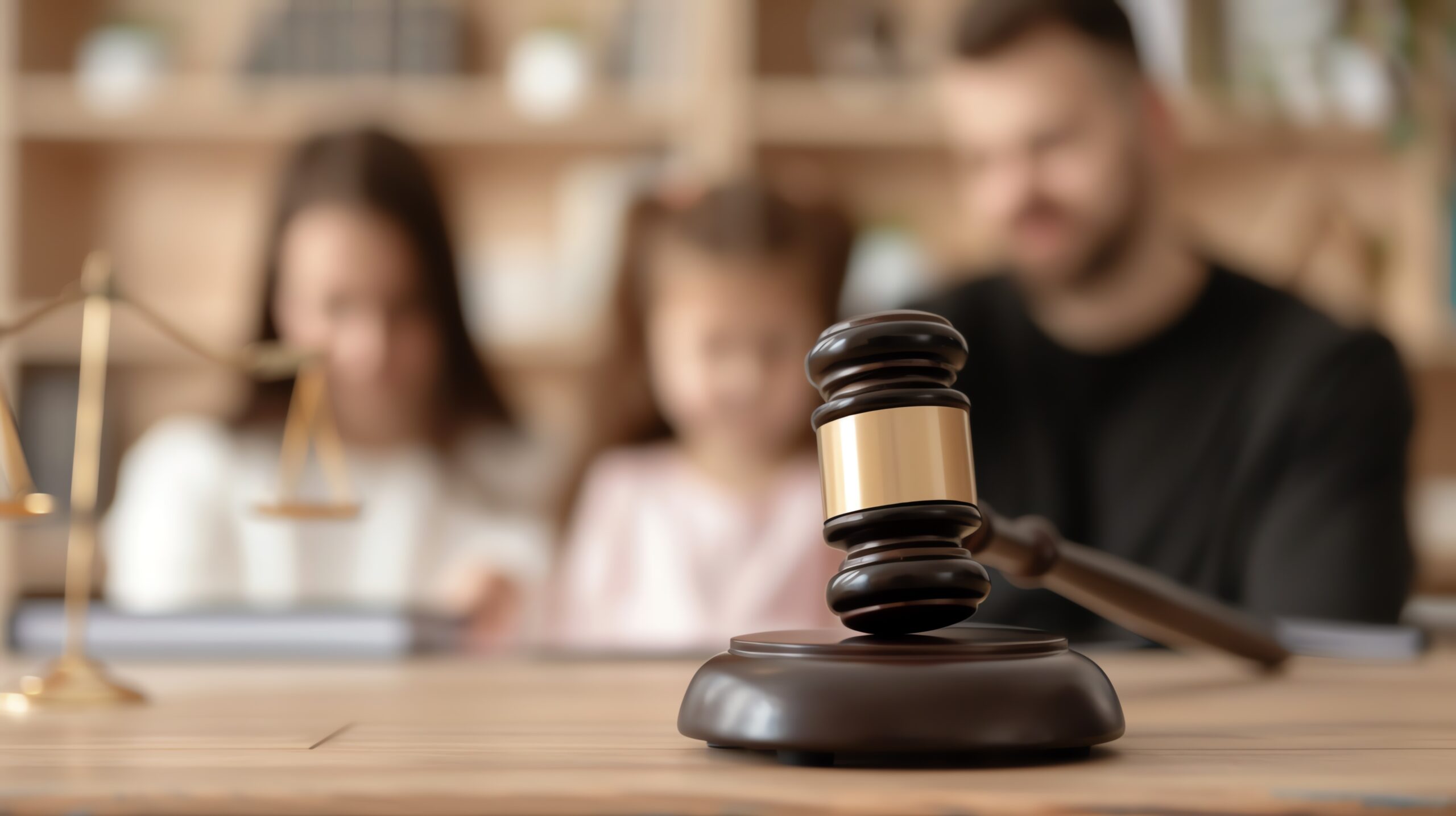 Wooden gavel on desk symbolizes justice. Family background suggests legal proceedings, reflecting importance of law in family matters.