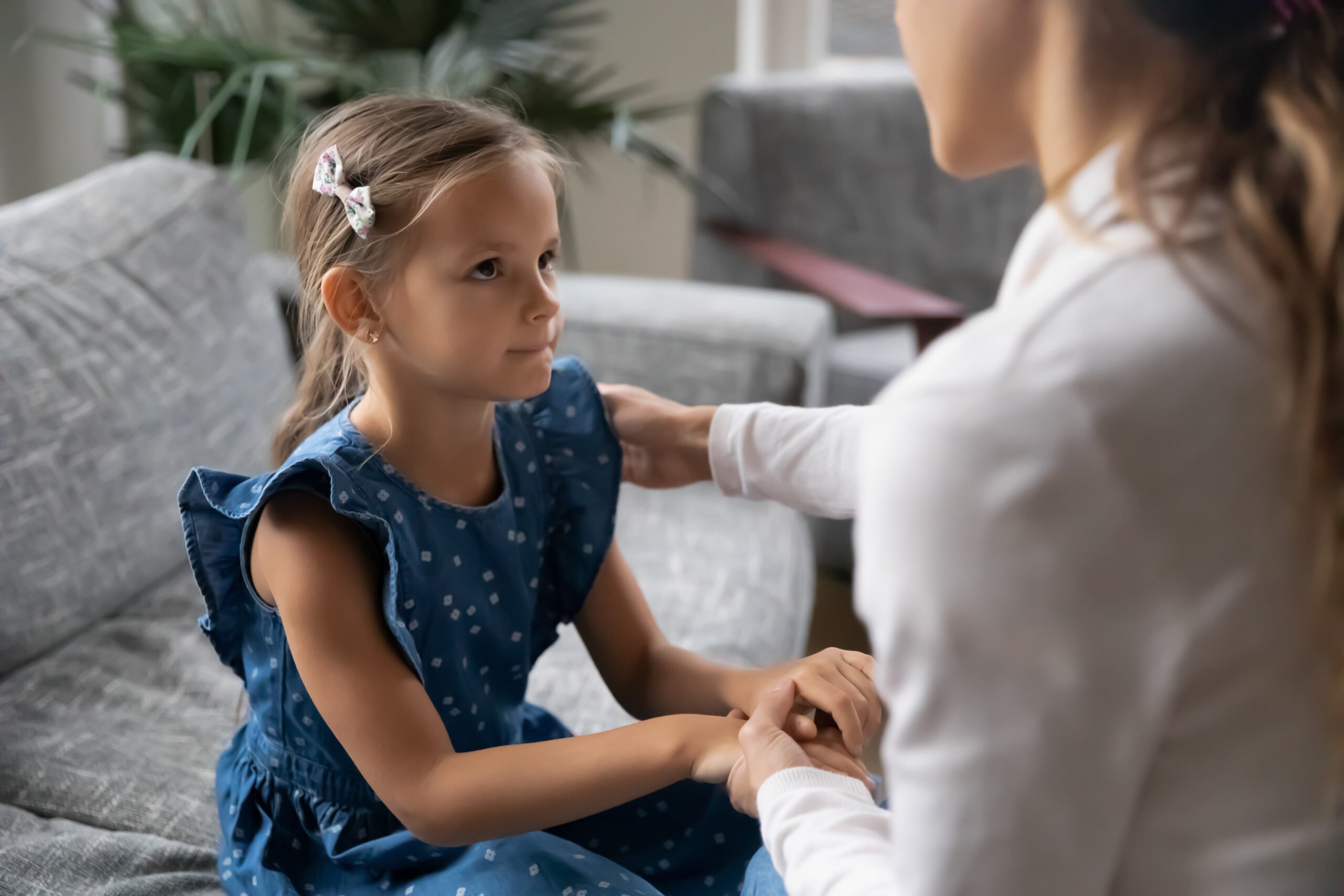 Close up loving young mother touching upset little daughter shoulder, expressing support and care, psychological help, mum comforting offended adorable cute girl, child psychologist concept