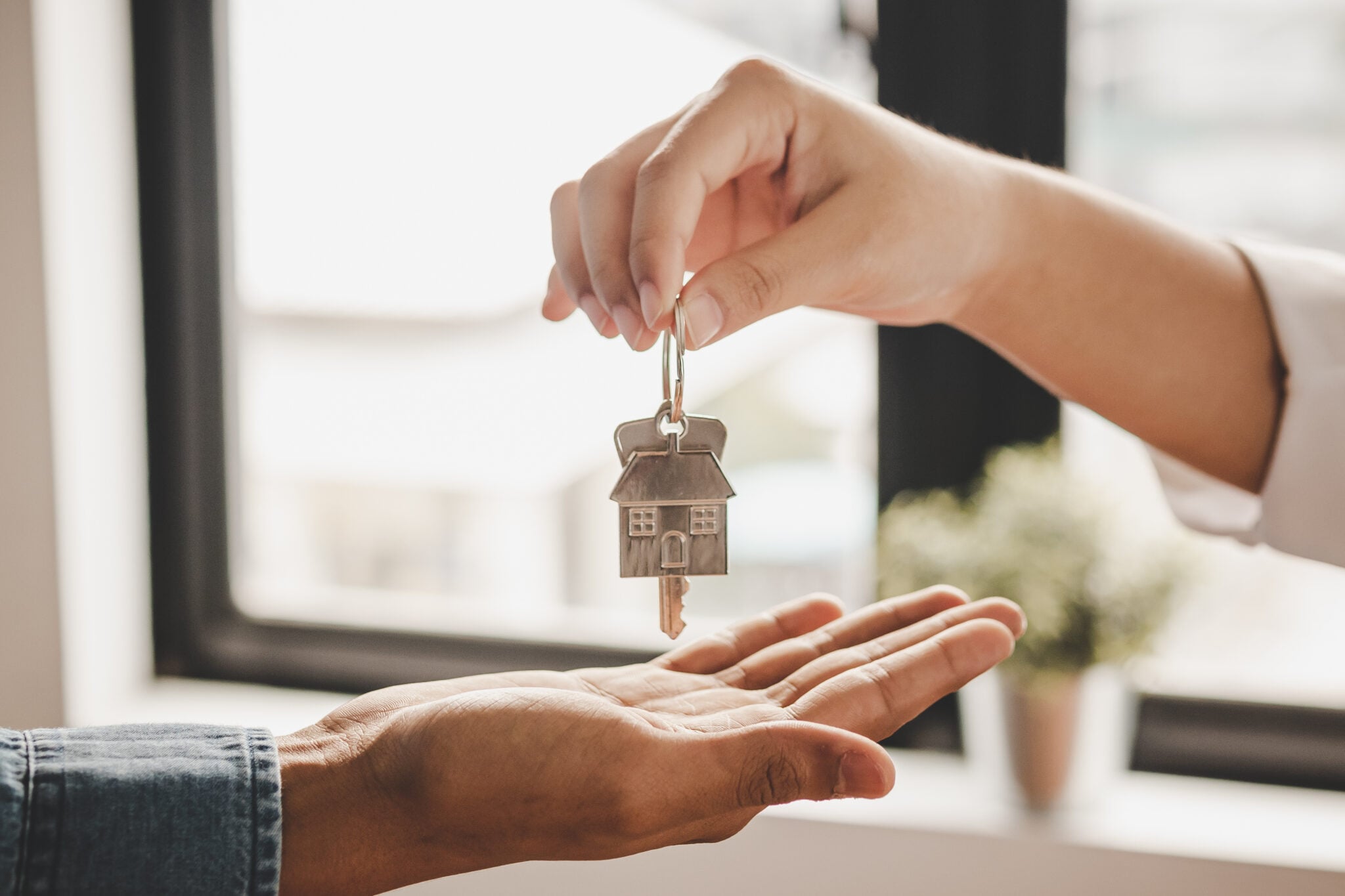 Close up hand of home,apartment agent or realtor was holding the key to the new landlord,tenant or rental.After the banker has approved and signed the purchase agreement successfully.Property concept.