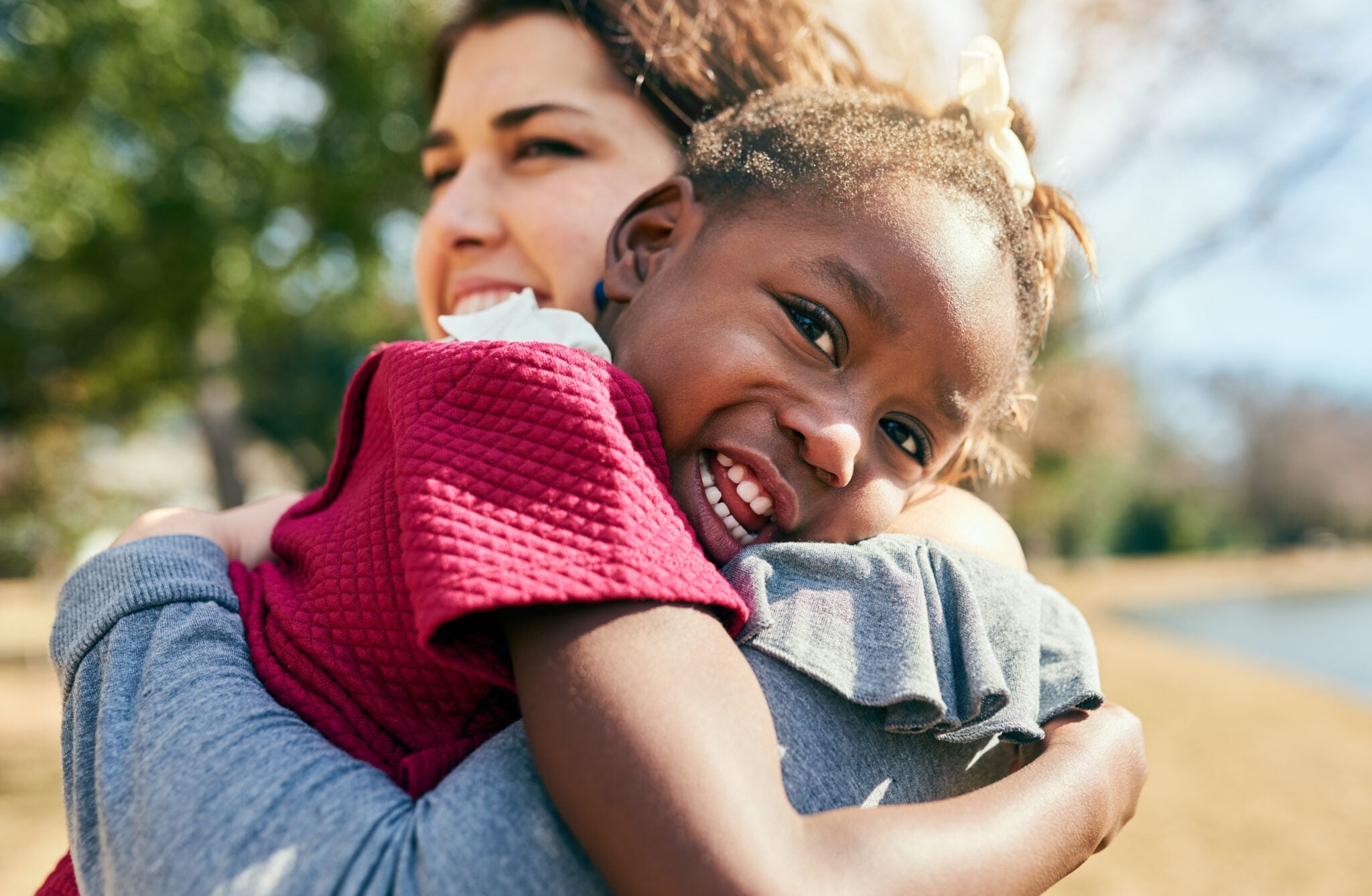 Hug, love and adoption with interracial family in nature for foster care, bonding and support. Child welfare, placement success and security with mother and girl in outdoors for happiness together.