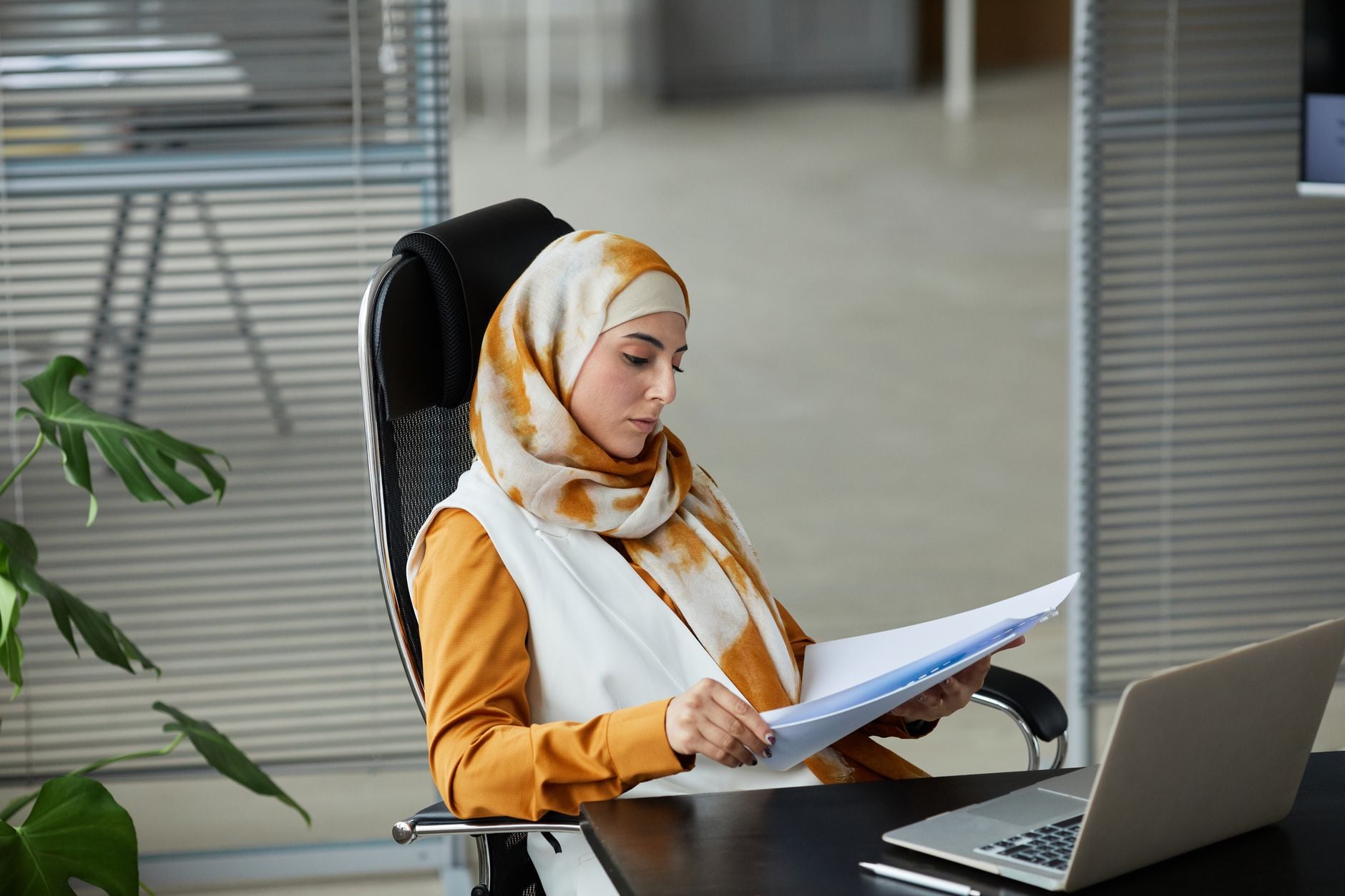 Woman in a hijab reviewing legal documents at her office desk